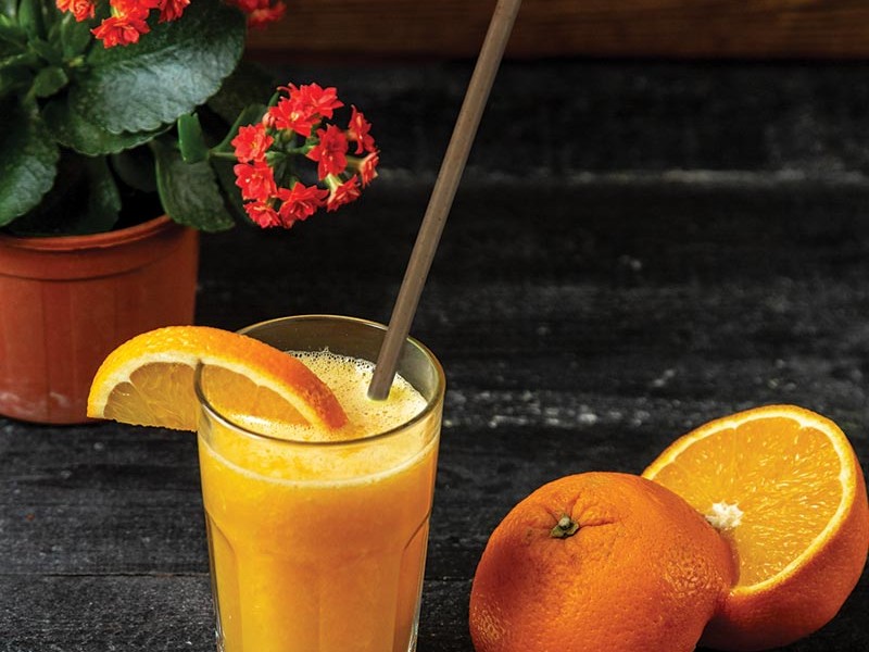A natural agave BioSip straw in a glass of fresh orange juice