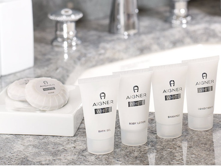The Aigner White range — bath gel, body lotion, shampoo, conditioner and wrapped soaps on a marble vanity