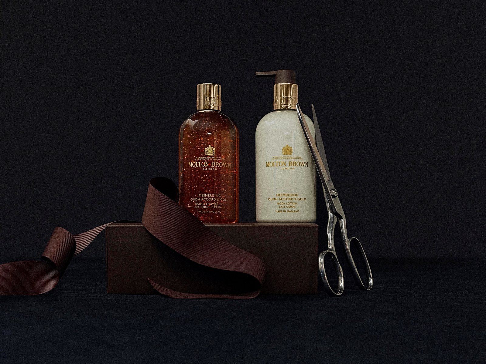 Molton Brown gift set with ribbon and scissors on a dark surface