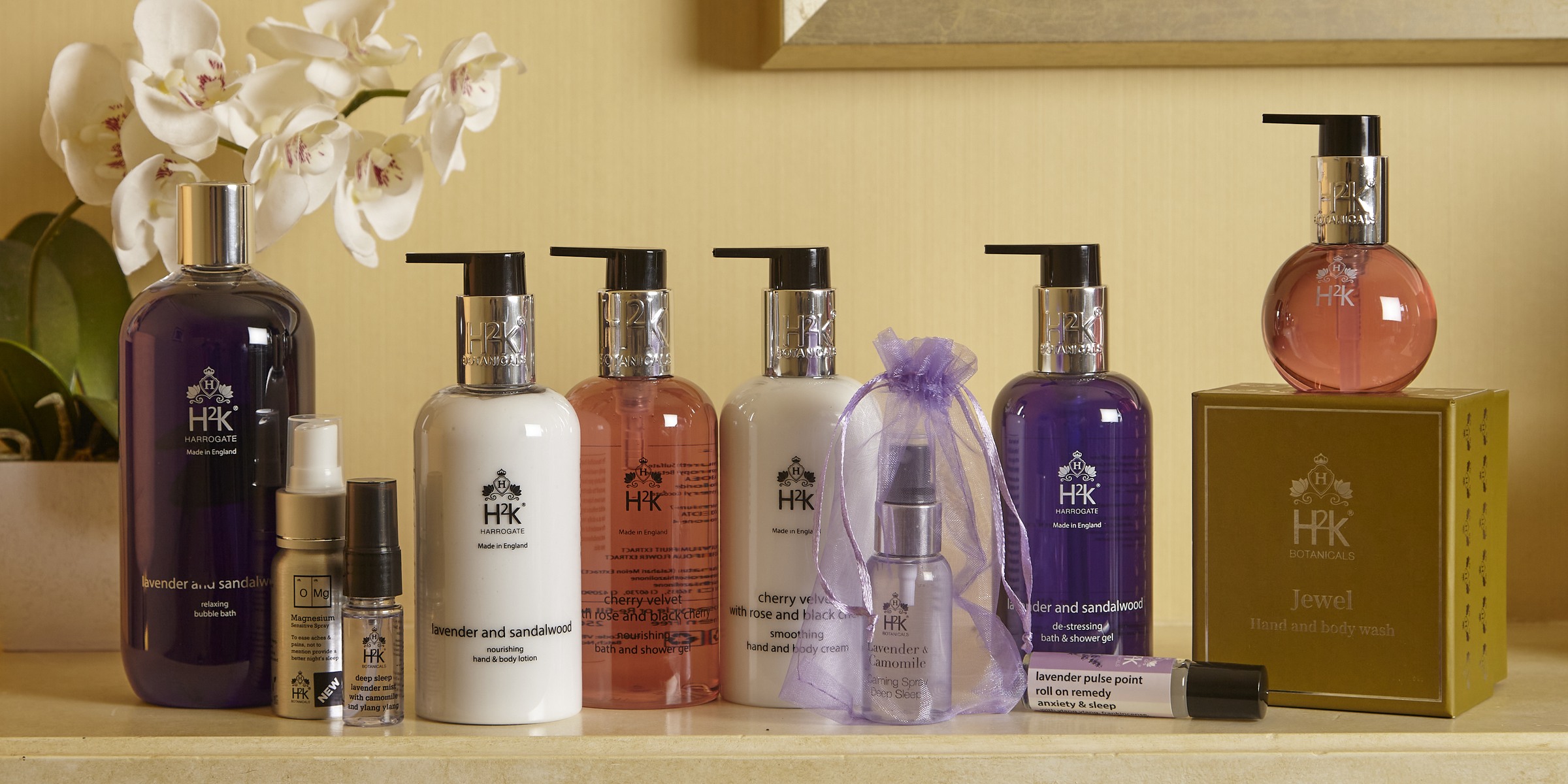 The H2K Botanicals range on a ledge — bubble bath, magnesium spray, deep sleep lavender mist, lotions, bath and shower gels, calming spray, pulse point roll-on and the Jewel hand and body wash