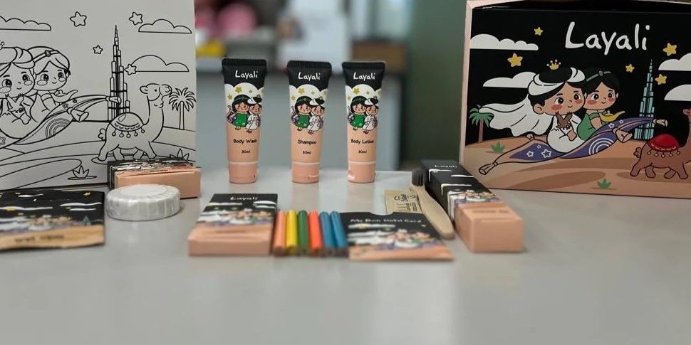 The Layali children’s amenity set laid out: body wash, shampoo and body lotion tubes, soap, dental kit, bamboo toothbrush, colouring sheet and crayons, guest card and presentation box