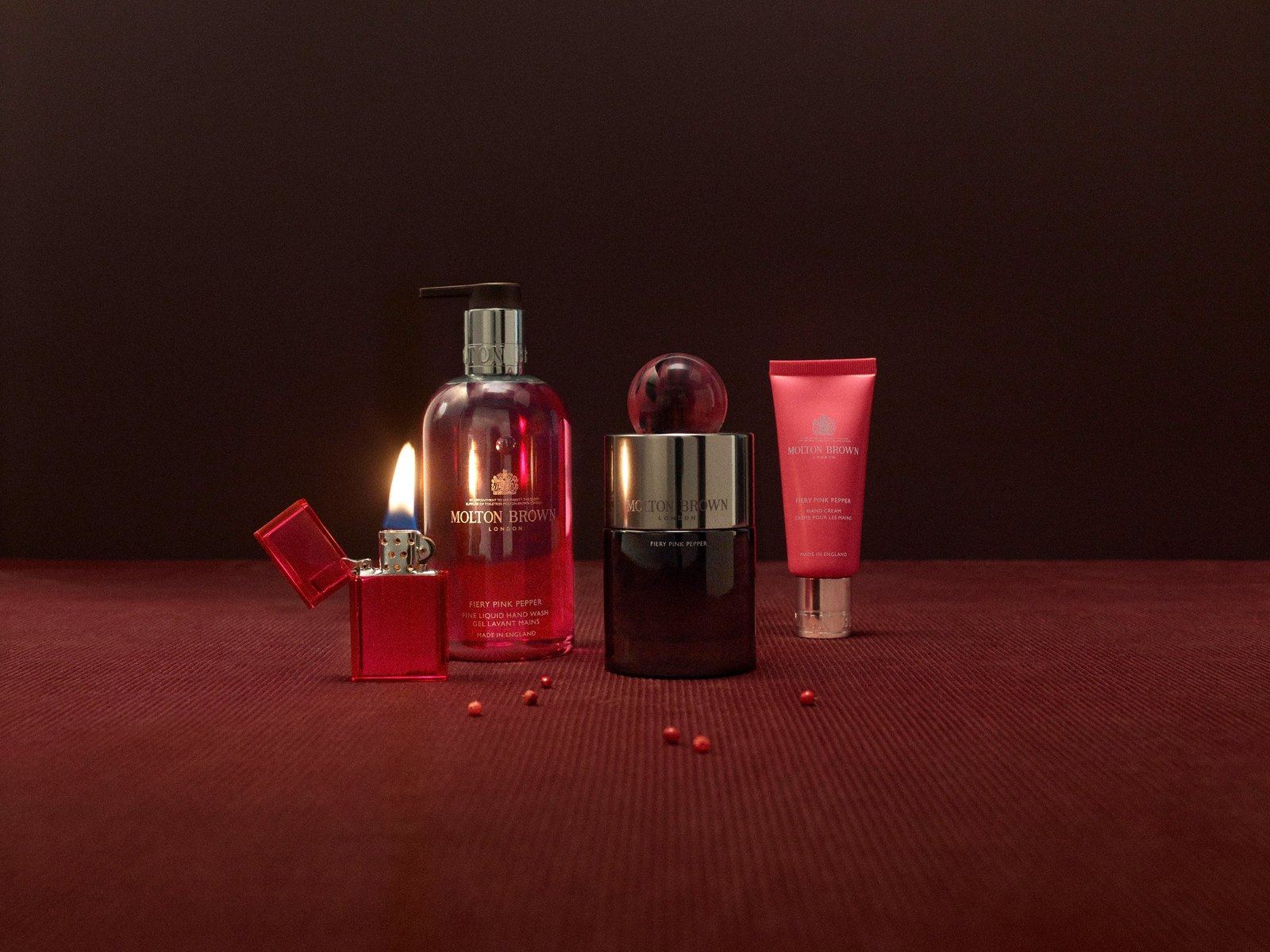 Molton Brown bath range and lit candle on a deep red setting