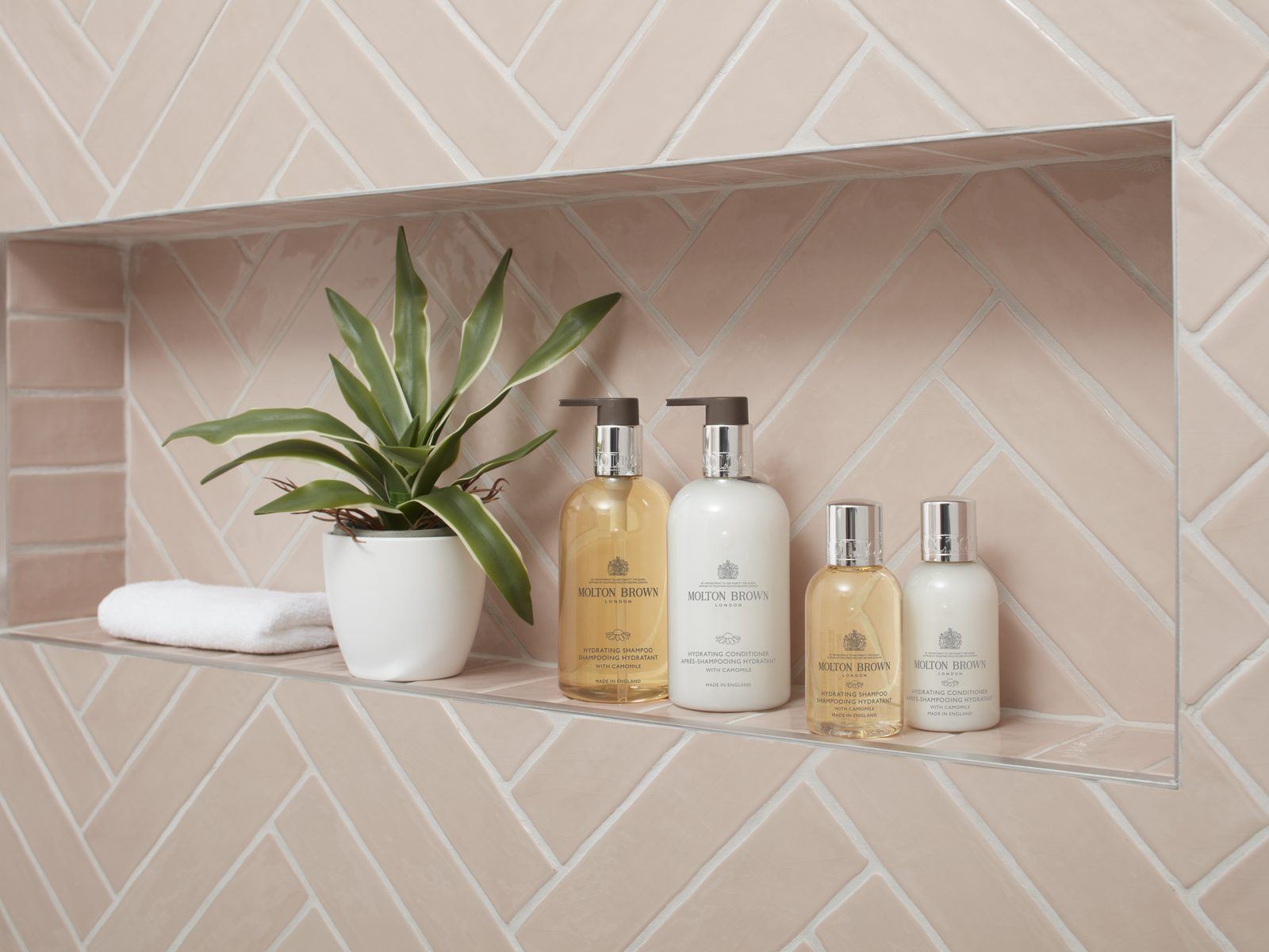 Molton Brown amenities arranged in a tiled bathroom niche