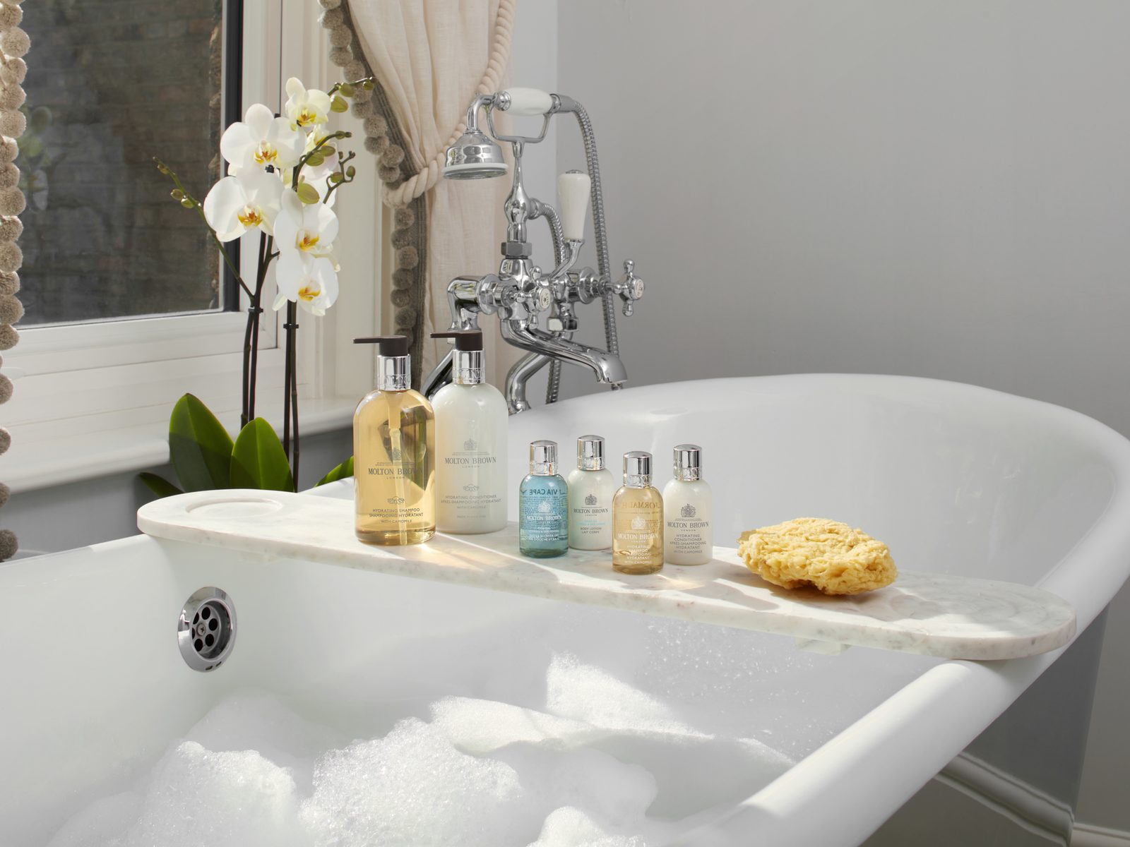 Molton Brown amenities on a roll-top bath in a resort bathroom