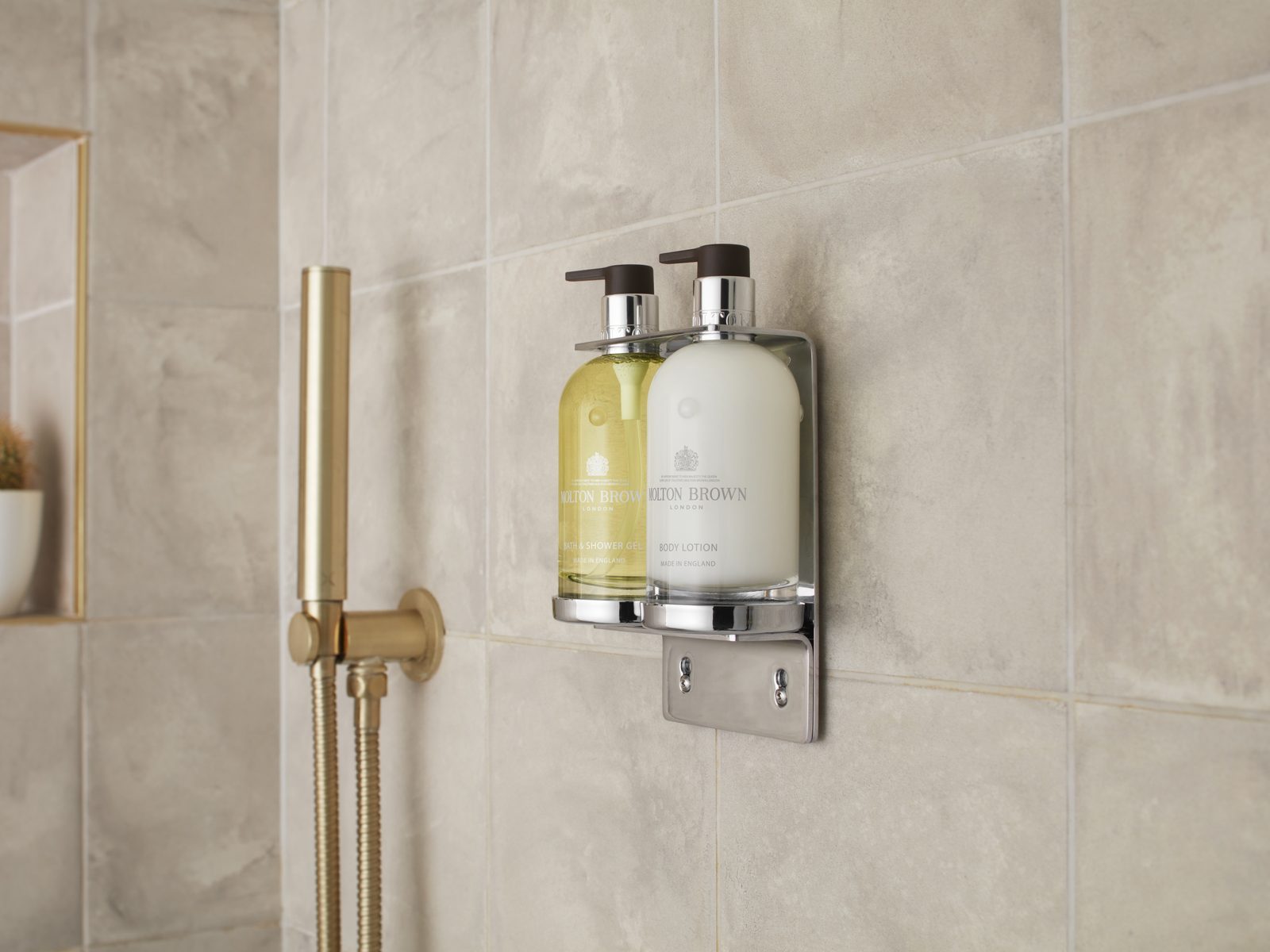 Molton Brown dispensers wall-mounted in a stone-tiled hotel shower
