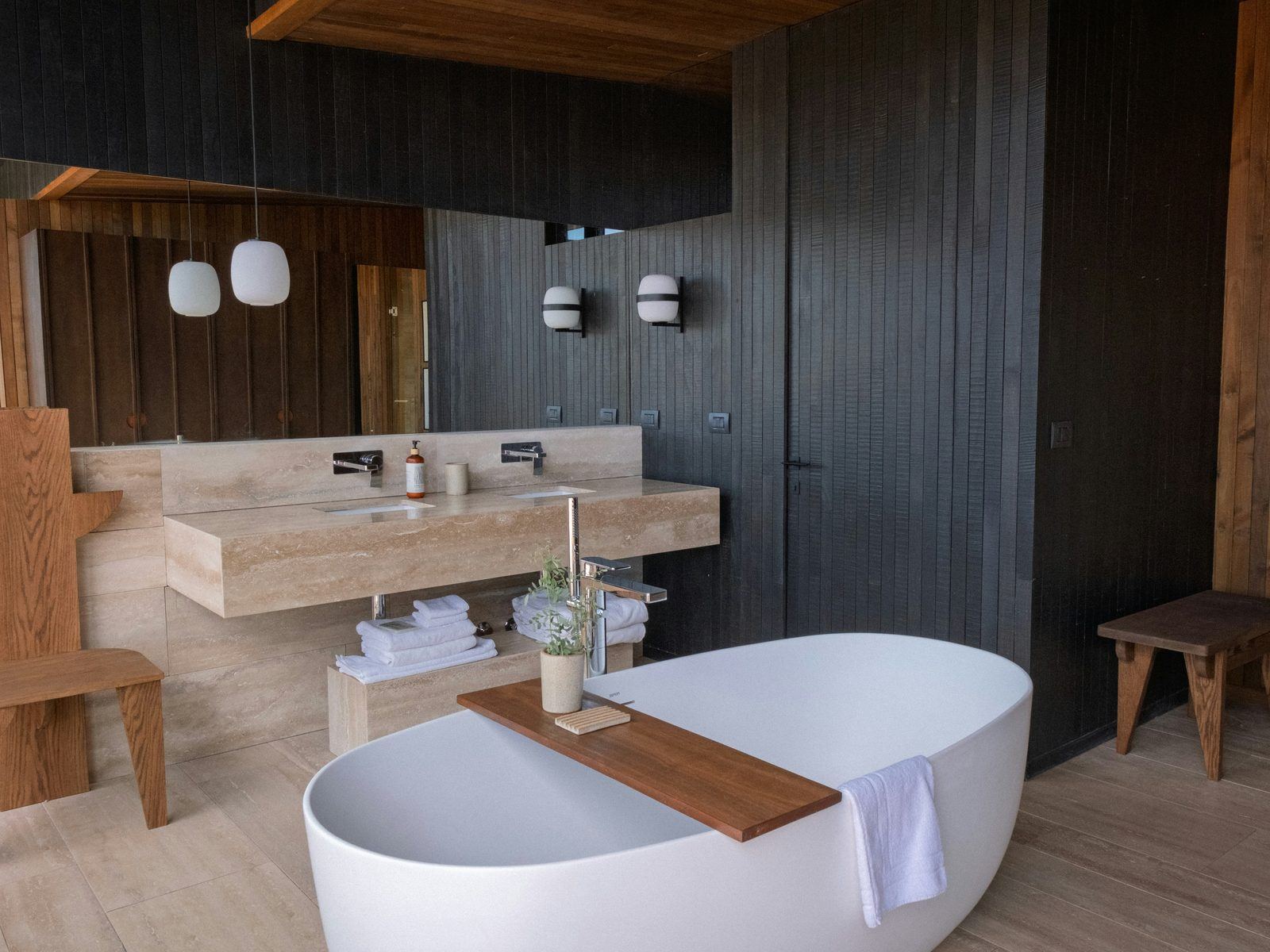 Freestanding bath and travertine vanity in a luxury resort bathroom