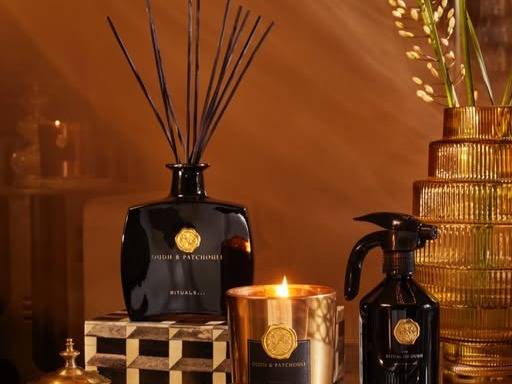 Rituals Oudh & Patchouli reed diffuser, lit gold candle and interior parfum spray on a brass tray