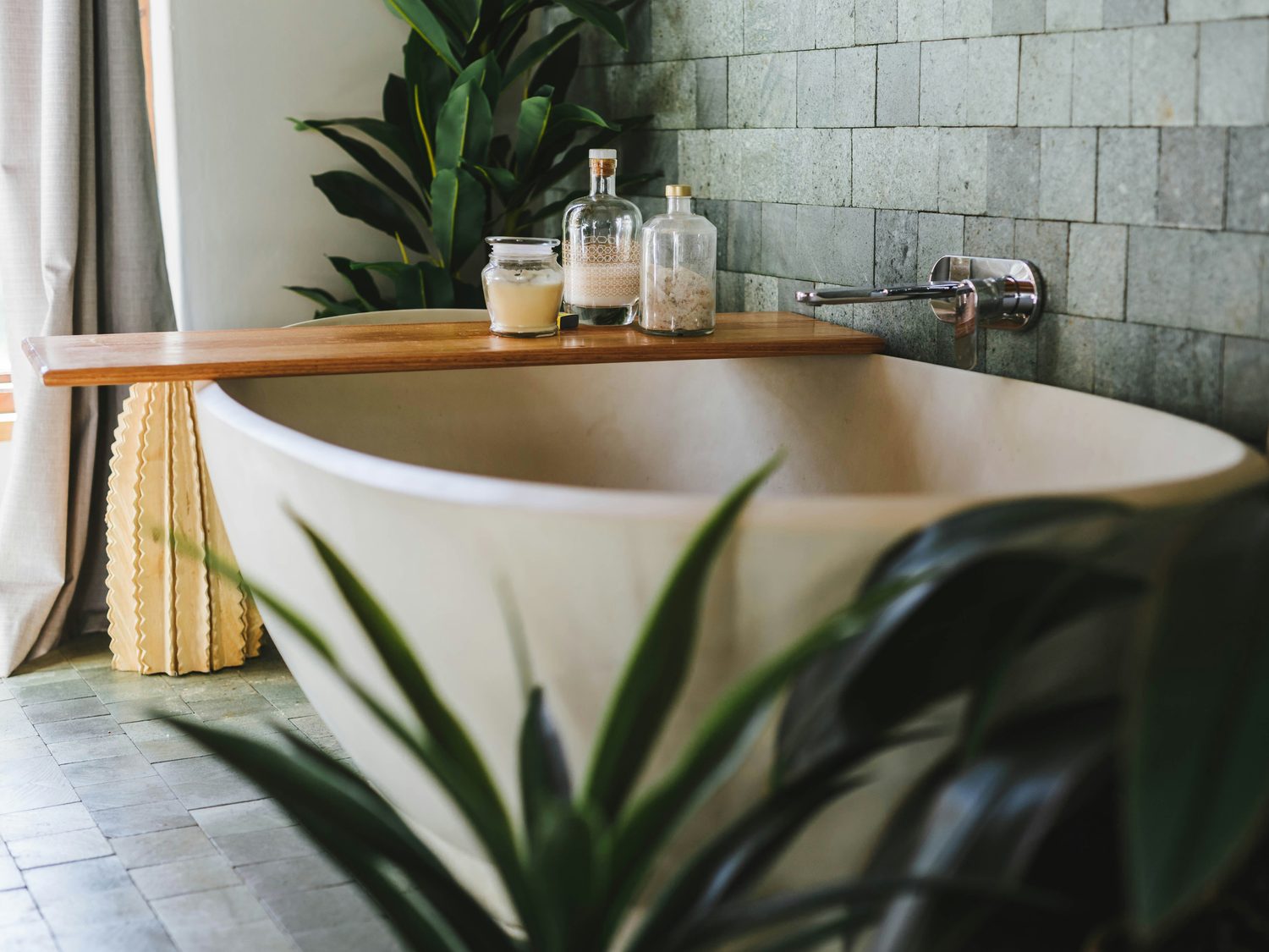 Freestanding bath with a timber caddy, candle and bath salts in a spa bathroom