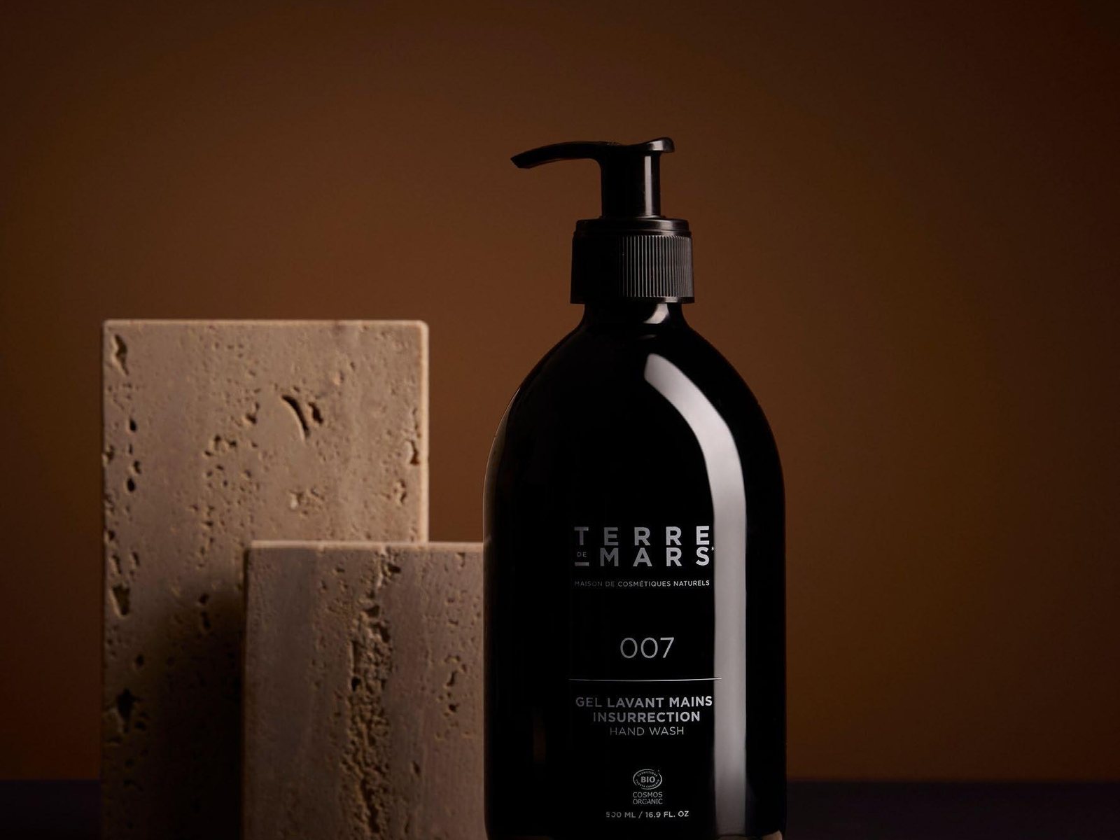 Terre de Mars 007 hand wash in a 500ml refillable bottle beside travertine blocks